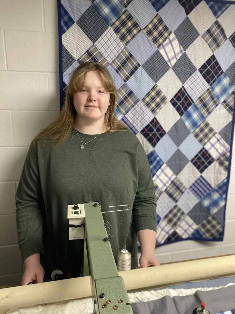 Abigail standing at her long-arm quilting machine