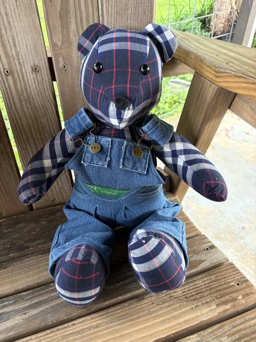 A plaid memory bear wearing overalls made from a pair of work overalls
