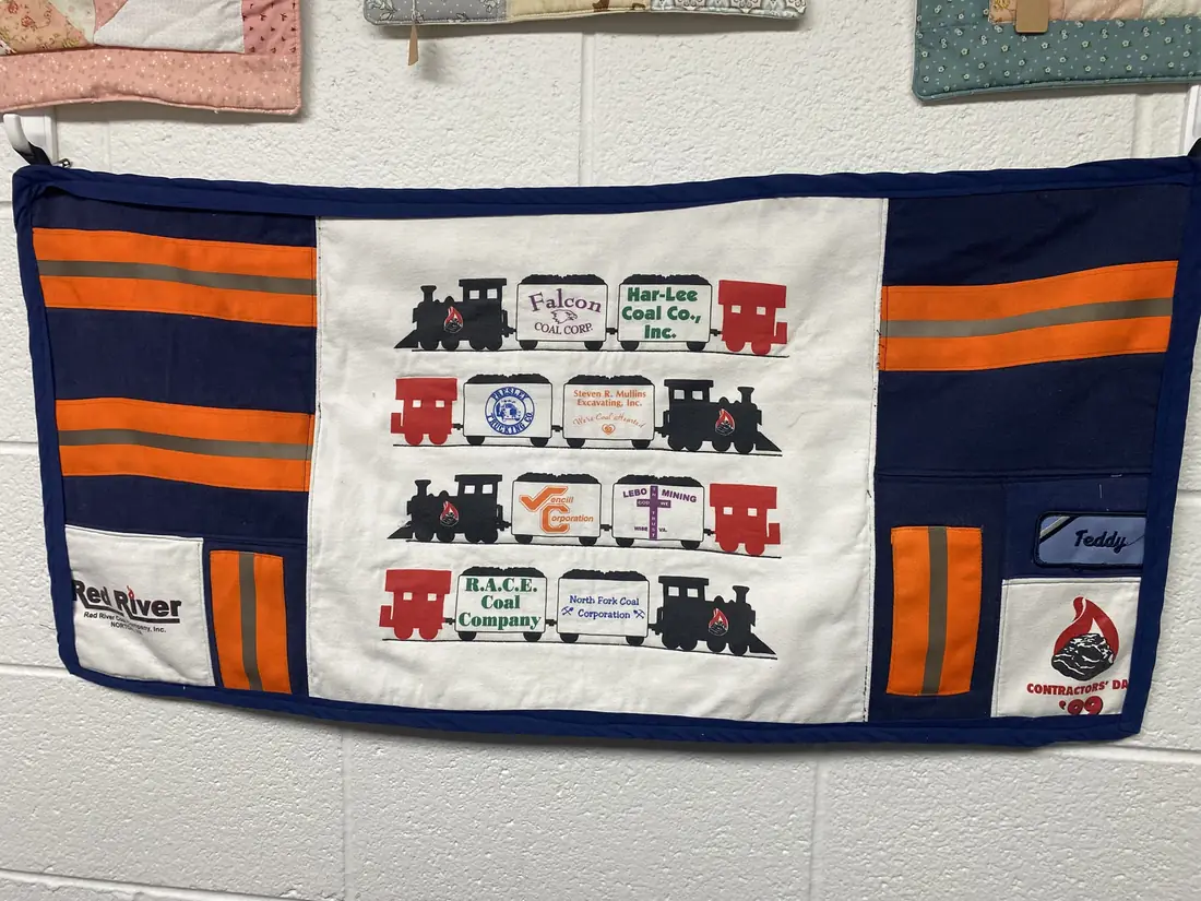 A wall hanging made from coal company work shirts, with a name patch